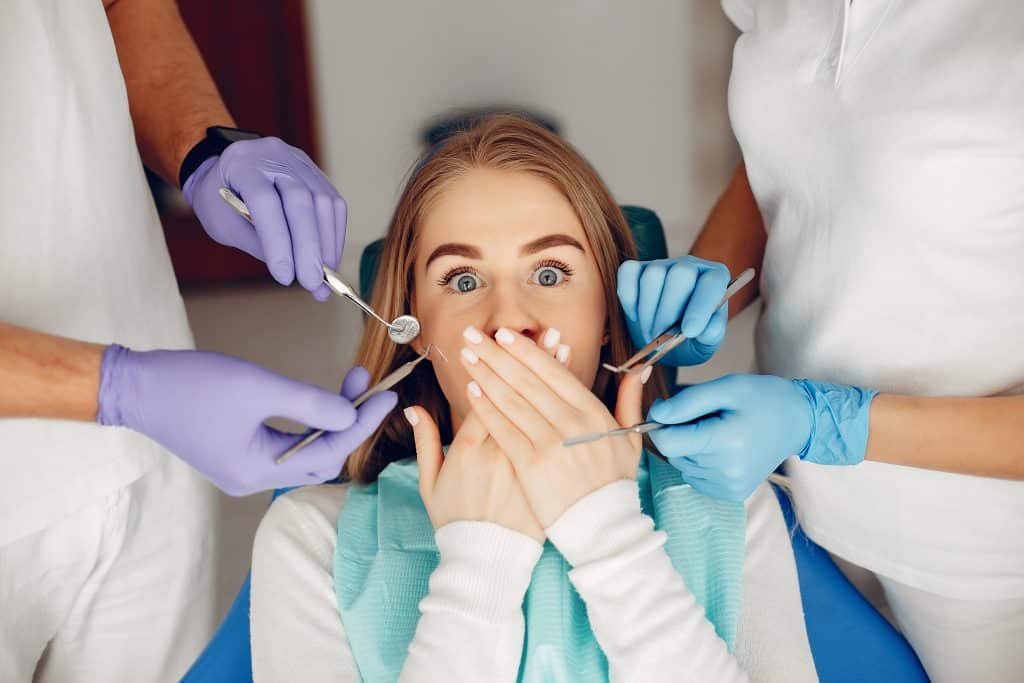 donna dal dentista che si copre la bocca per non far vedere le macchie verdi sui denti