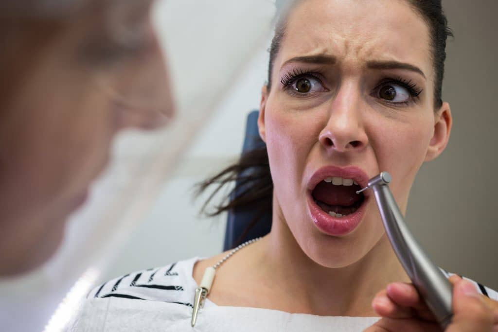 Donna con paura dal dentista in seduta odontoiatrica