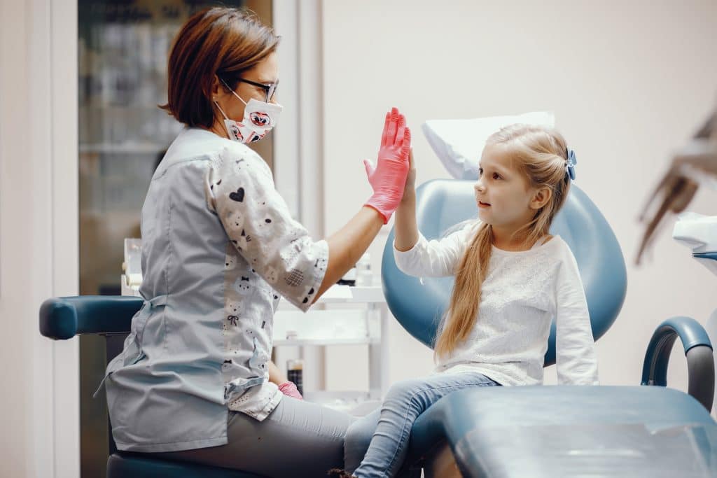 bambina batte il cinque della pedodonzista per scacciare la paura del dentista