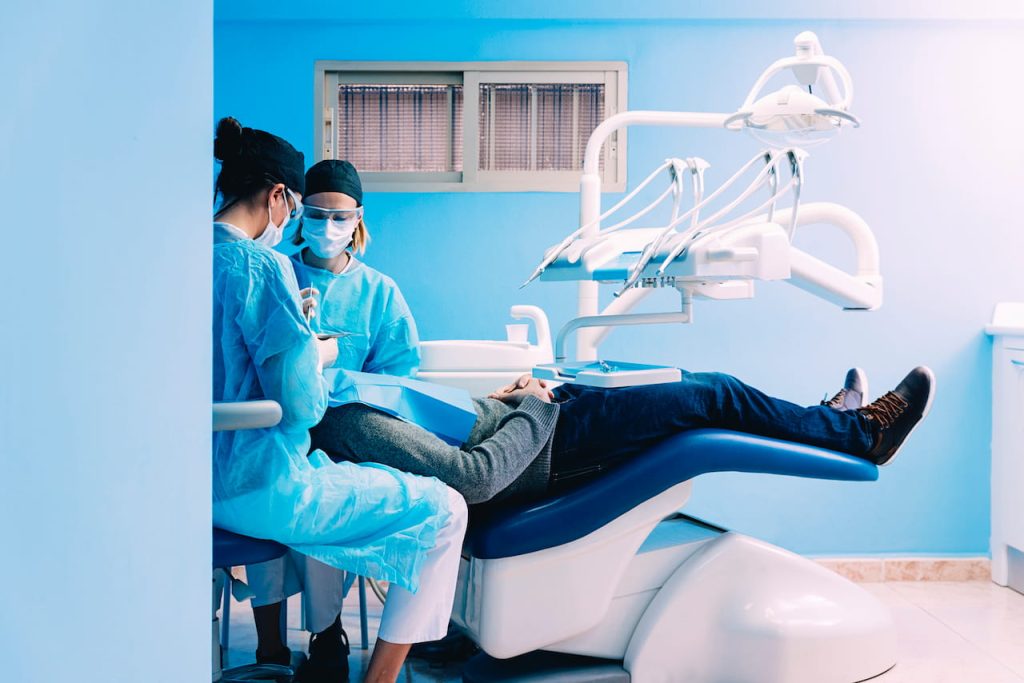 dentisti operano paziente in poltrona mentre è sotto effetto di sedazione cosciente endovenosa