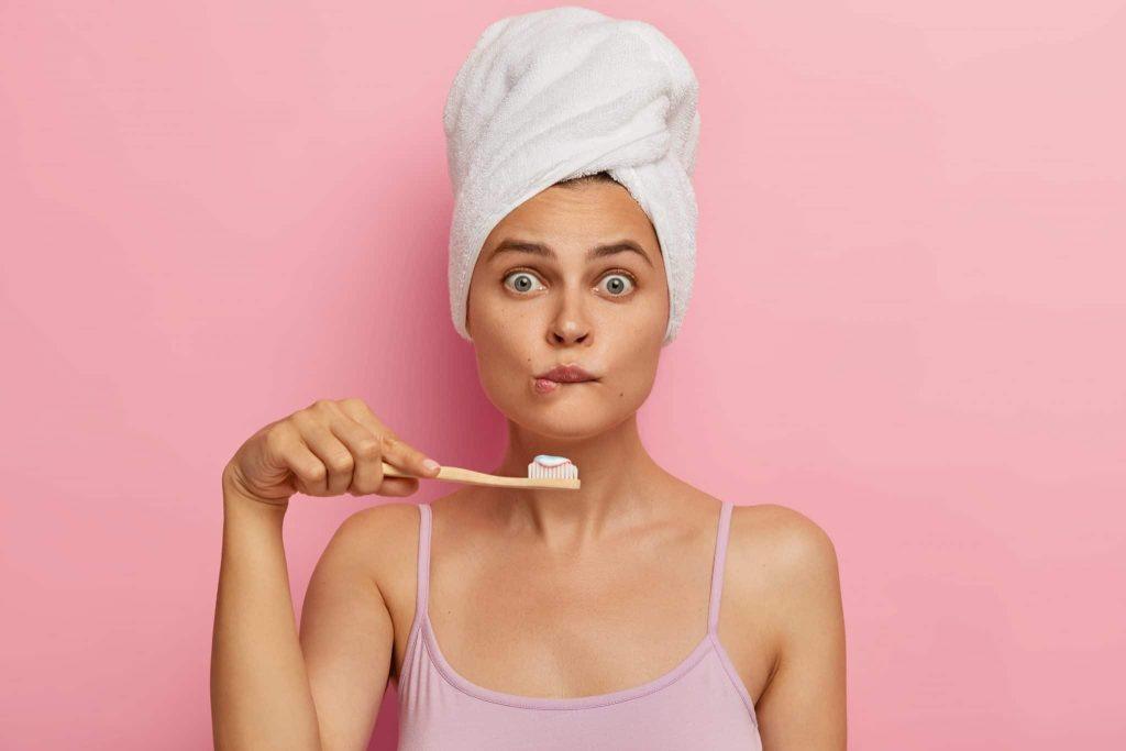 Donna che si lava i denti ma non apre bocca perchè ha i denti macchiati