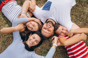genitori e figli in cerchio che sorridono - in preparazione a prima visita dal dentista per bambini