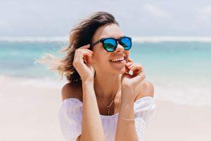 Donna al mare che sorride - proteggere i denti in estate