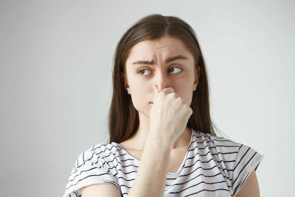 Donna che si tappa il naso per alitosi rimedi