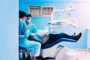 dentisti operano paziente in poltrona mentre è sotto effetto di sedazione cosciente endovenosa